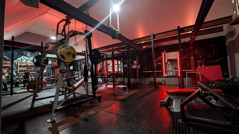 Squat racks and lifting platforms under red strip lighting in the top room.